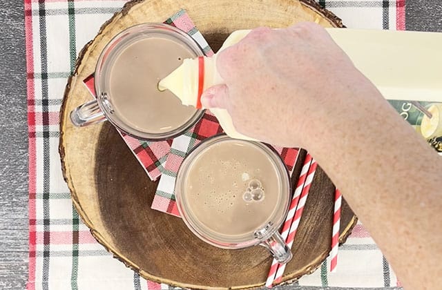 Pouring eggnog into glass mugs with chocolate milk