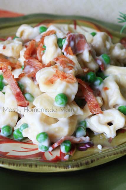 A green plate with bacon tortellini being served.