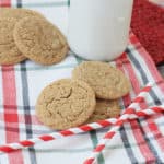 Ginger snaps cookies on a plaid napkin with milk in the background