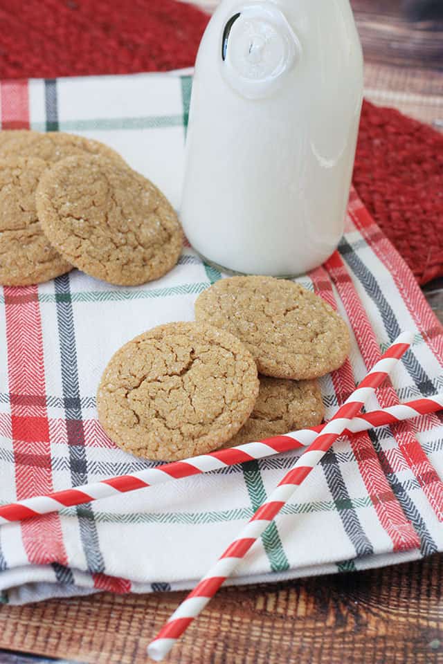 Ginger snaps cookies on a plaid napkin with milk in the background