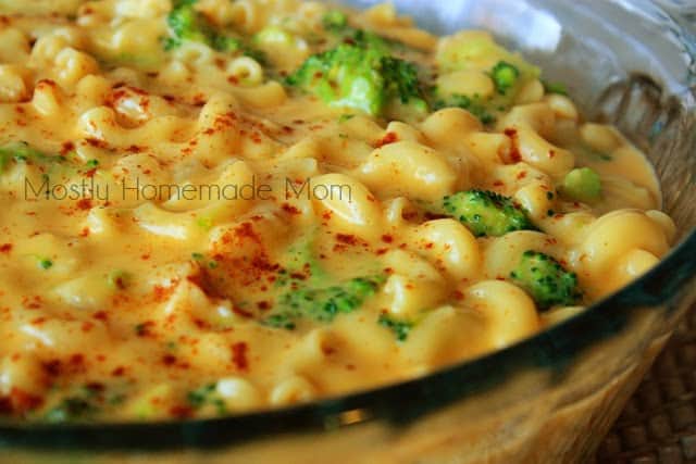 Broccoli mac and cheese being served in a glass round baking dish