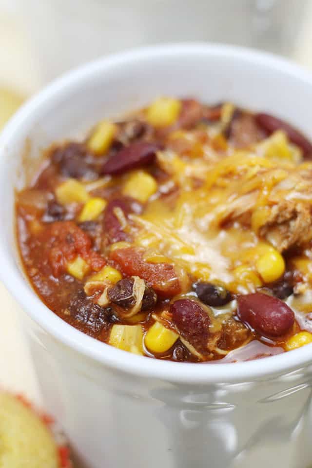Crockpot Chicken Chili in a white soup mug topped with cheese