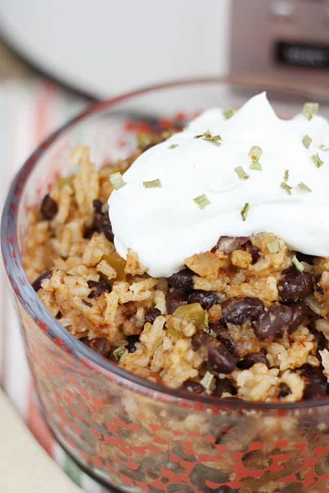 Crockpot black beans and rice in a glass bowl topped with sour cream