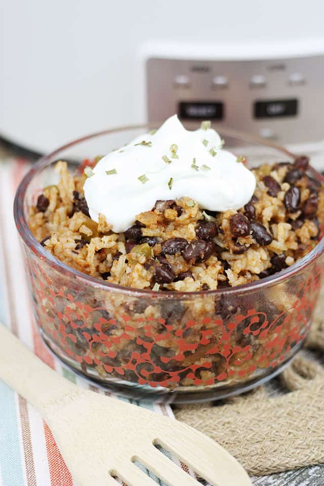 Crockpot black beans and rice in a glass bowl in front of a white slow cooker