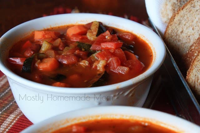 A white bowl of roasted vegetable chili on a red placemat