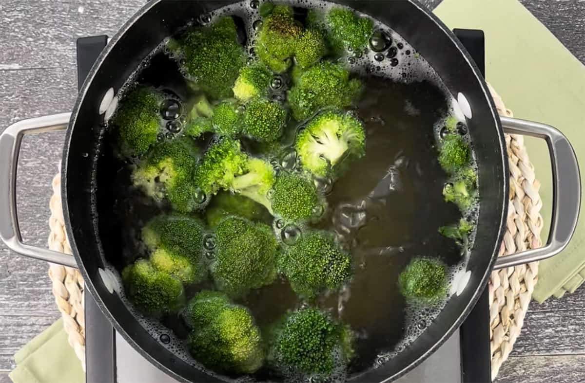 Broccoli boiling in water on a stove.
