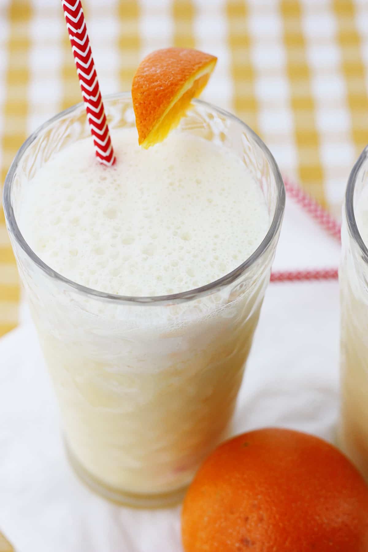 A glass of copycat Orange Julius with a straw and orange slice garnish.
