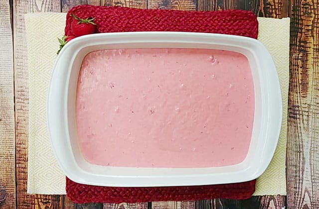 Strawberry jello cake batter in a white baking dish