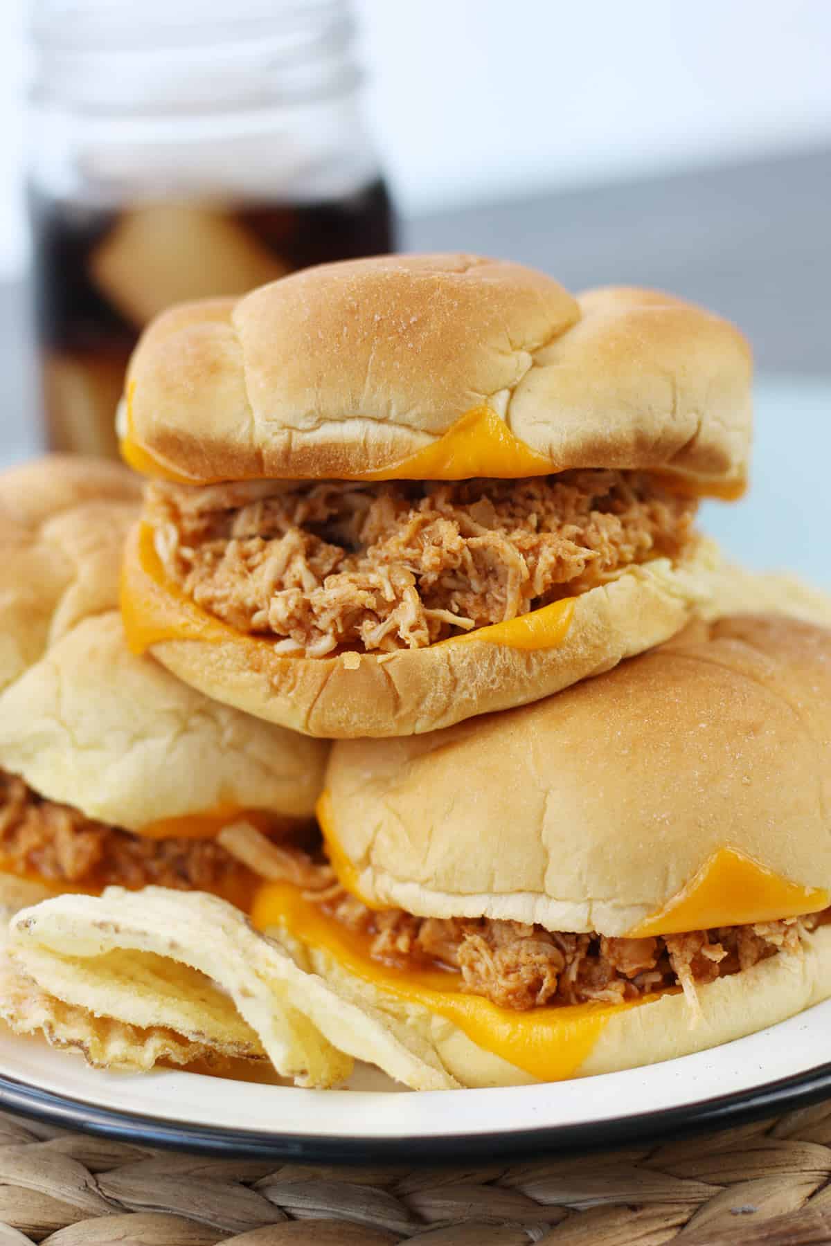 A stack of three bbq chicken sandwiches on a white plate.