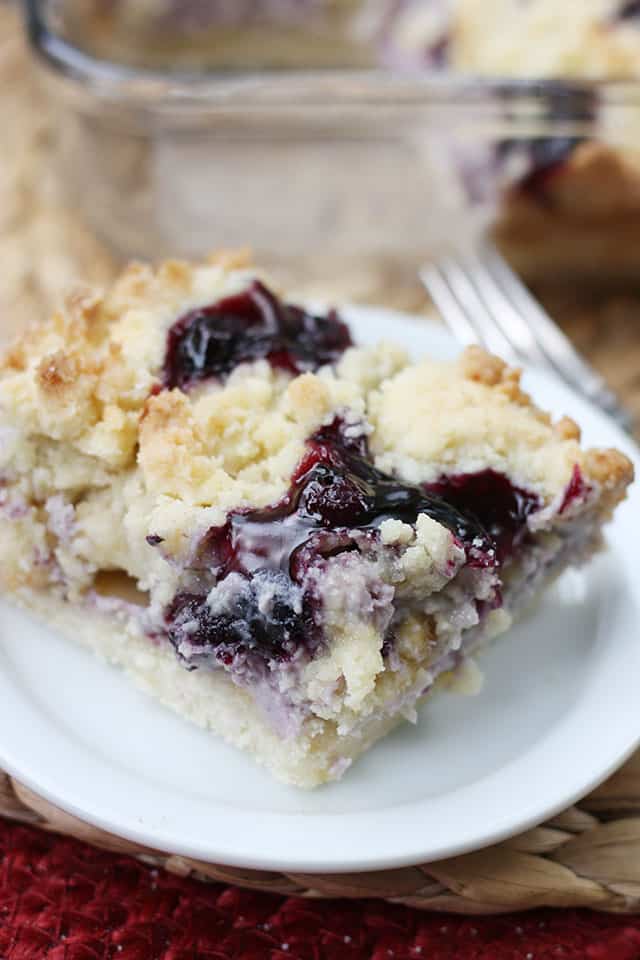 A close up photo of blueberry cobbler sugar cookie square on a white appetizer plate