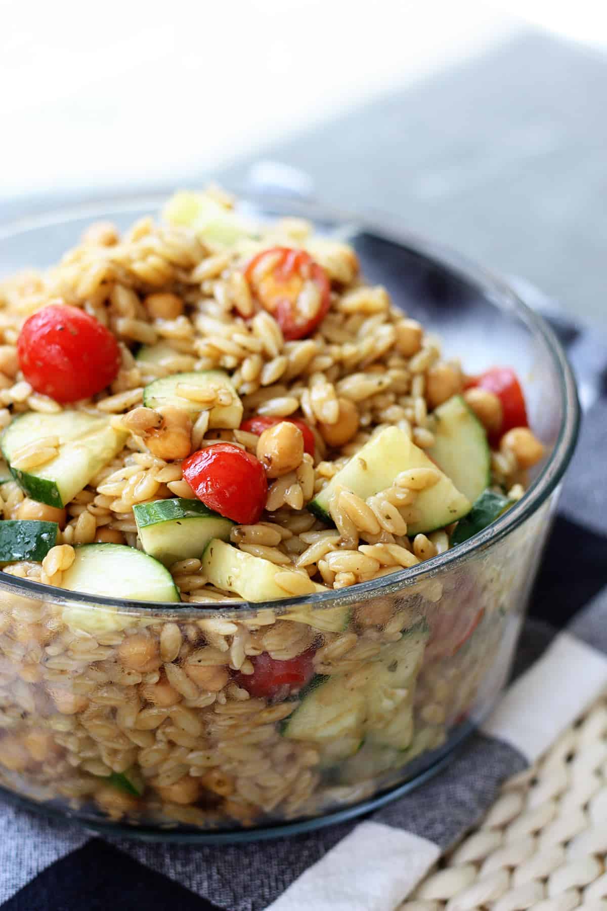 A glass bowl filled with orzo pasta salad.