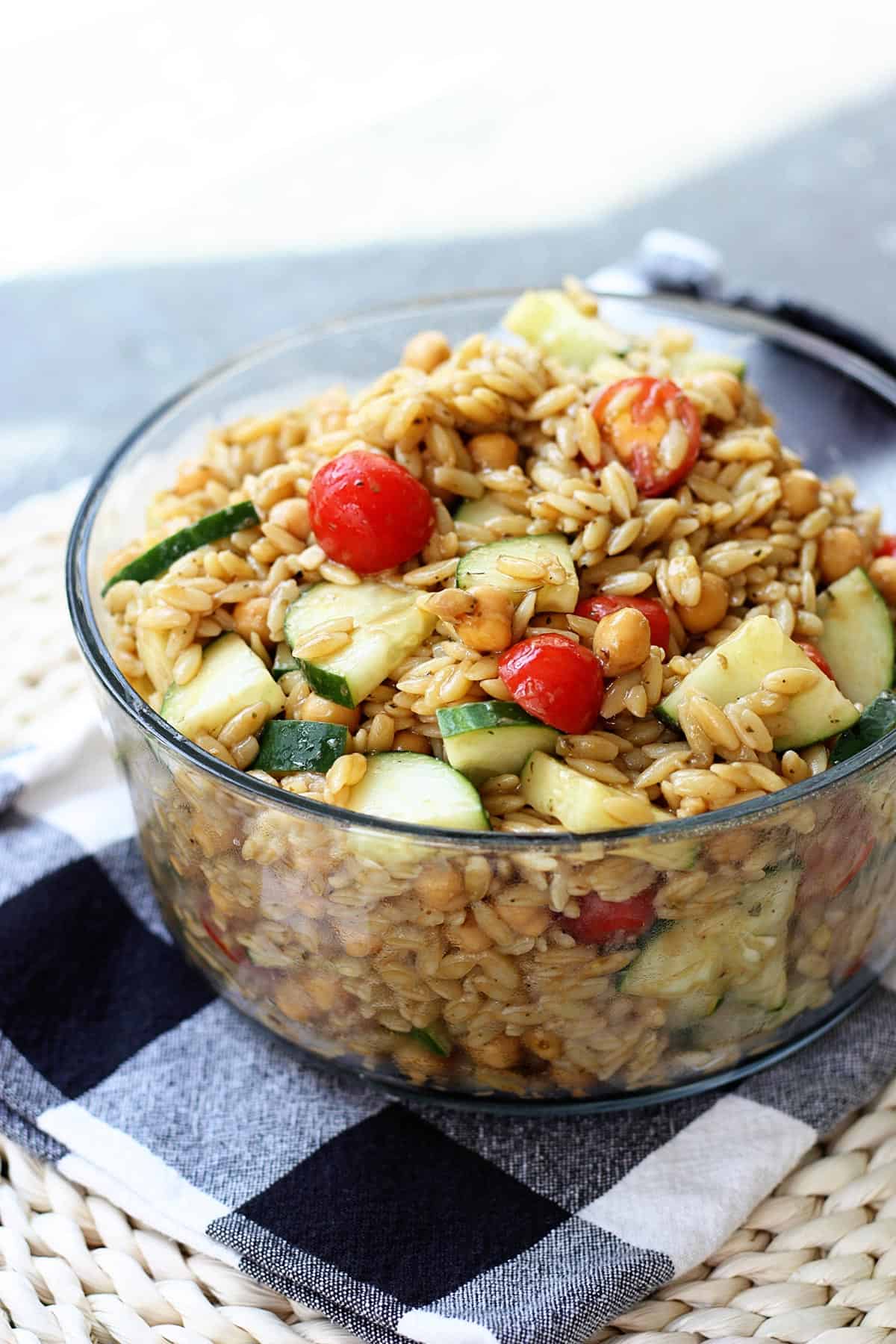 Orzo pasta salad in a glass serving bowl.