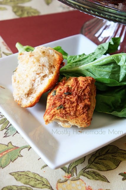 A piece of savory monkey bread on a white plate with basil leaves underneath