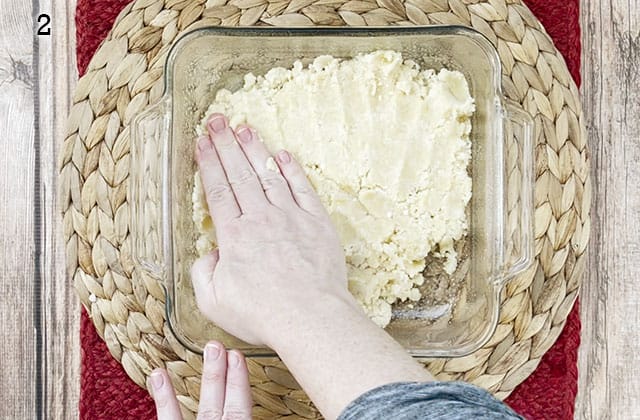 Pressing sugar cookie mix into a glass baking dish