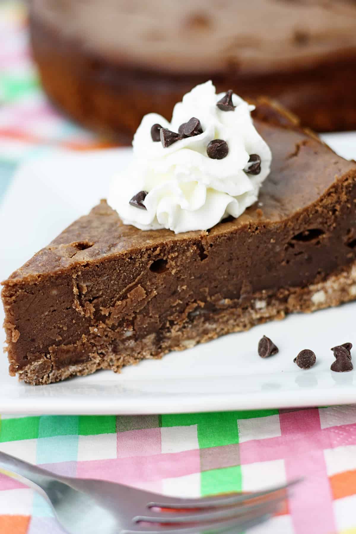 A slice of brownie cheesecake topped with whipped cream.