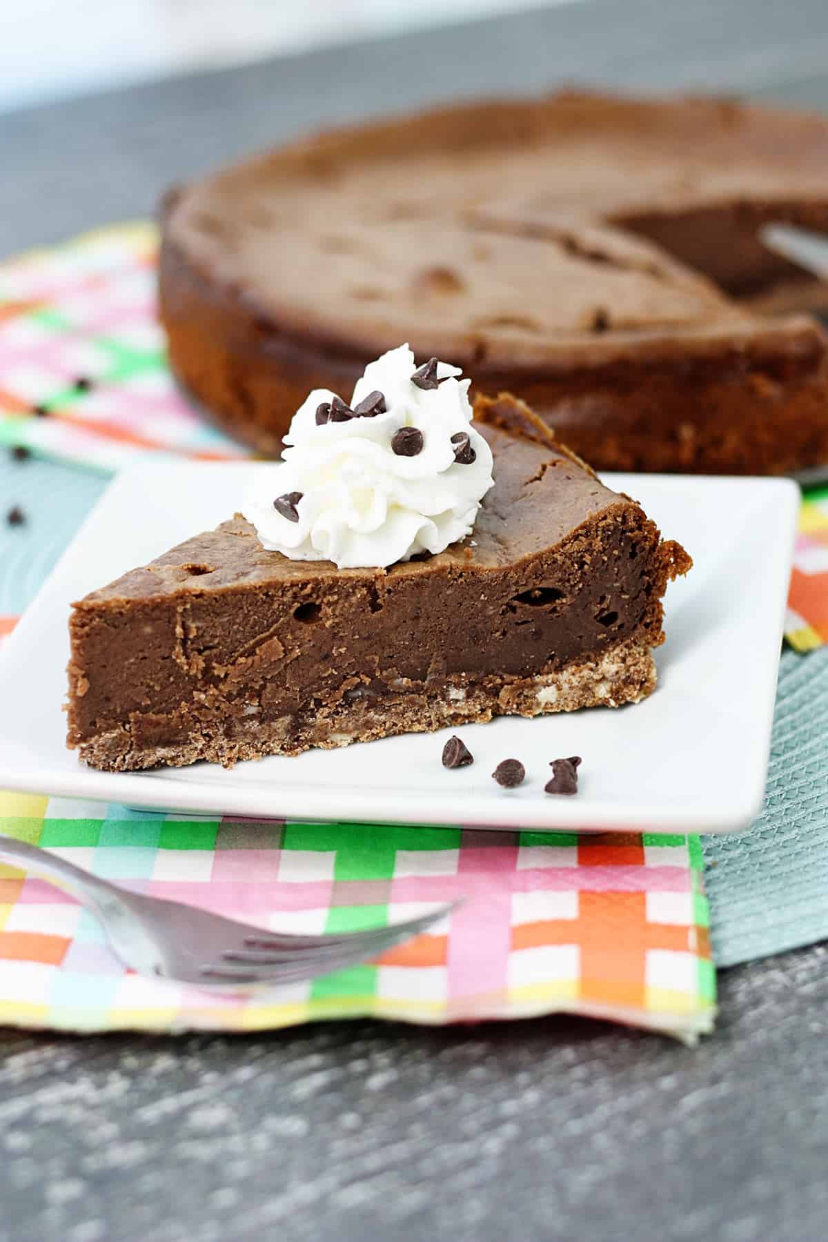 A slice of brownie cheesecake on a white plate.