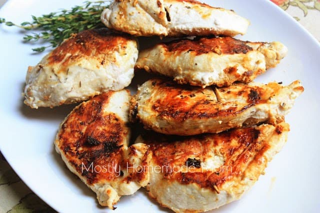 Pieces of lemon grilled chicken breast on a white oval platter being served