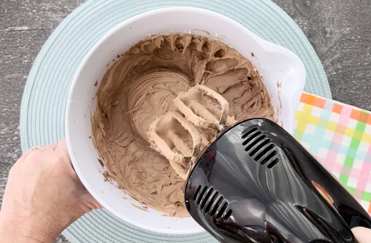 Beating the cheesecake batter with a hand mixer.