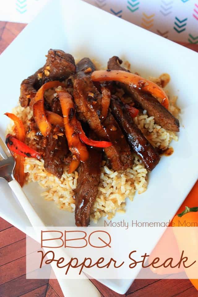 BBQ pepper steak over brown rice on a white plate with a fork