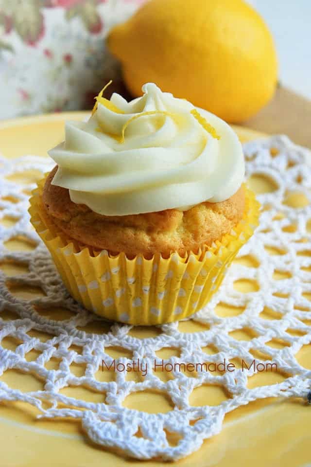 A lemon pudding cupcake in a yellow cupcake liner on a white doily