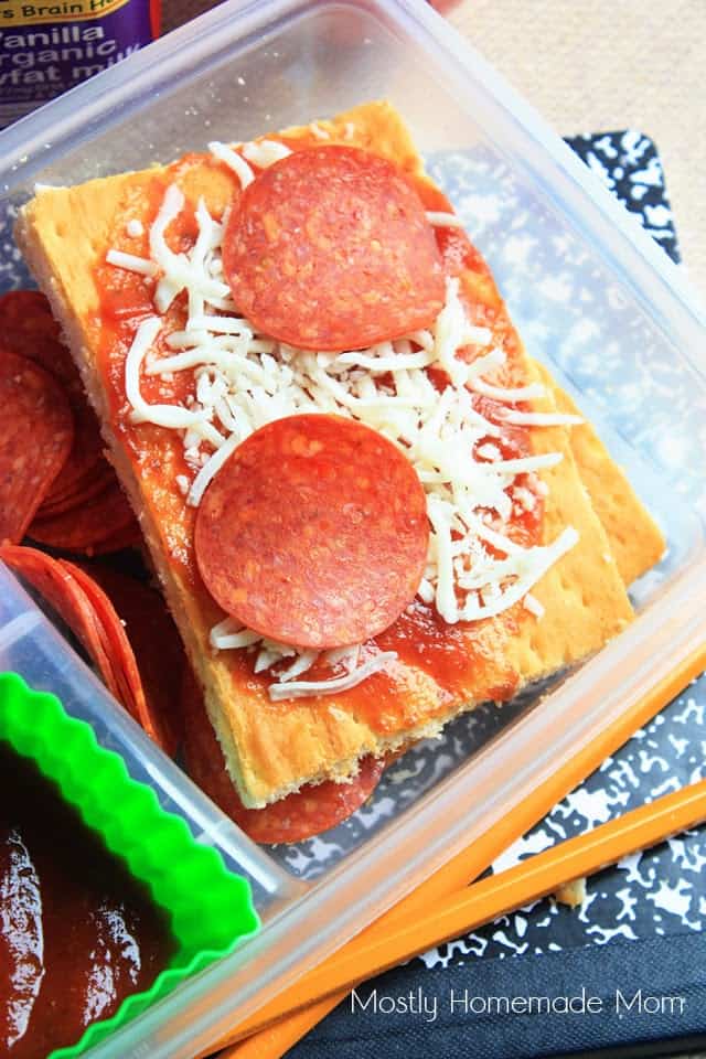 A slice of DIY pizza lunchables in a plastic takeout container topped with pepperoni