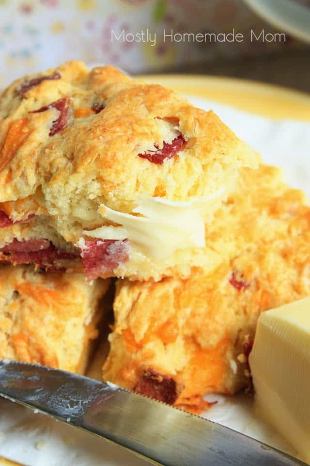 A bacon cheddar scone with butter spread on one slice