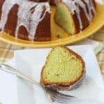 Pistachio cake on a serving platter with a slice on a small white plate