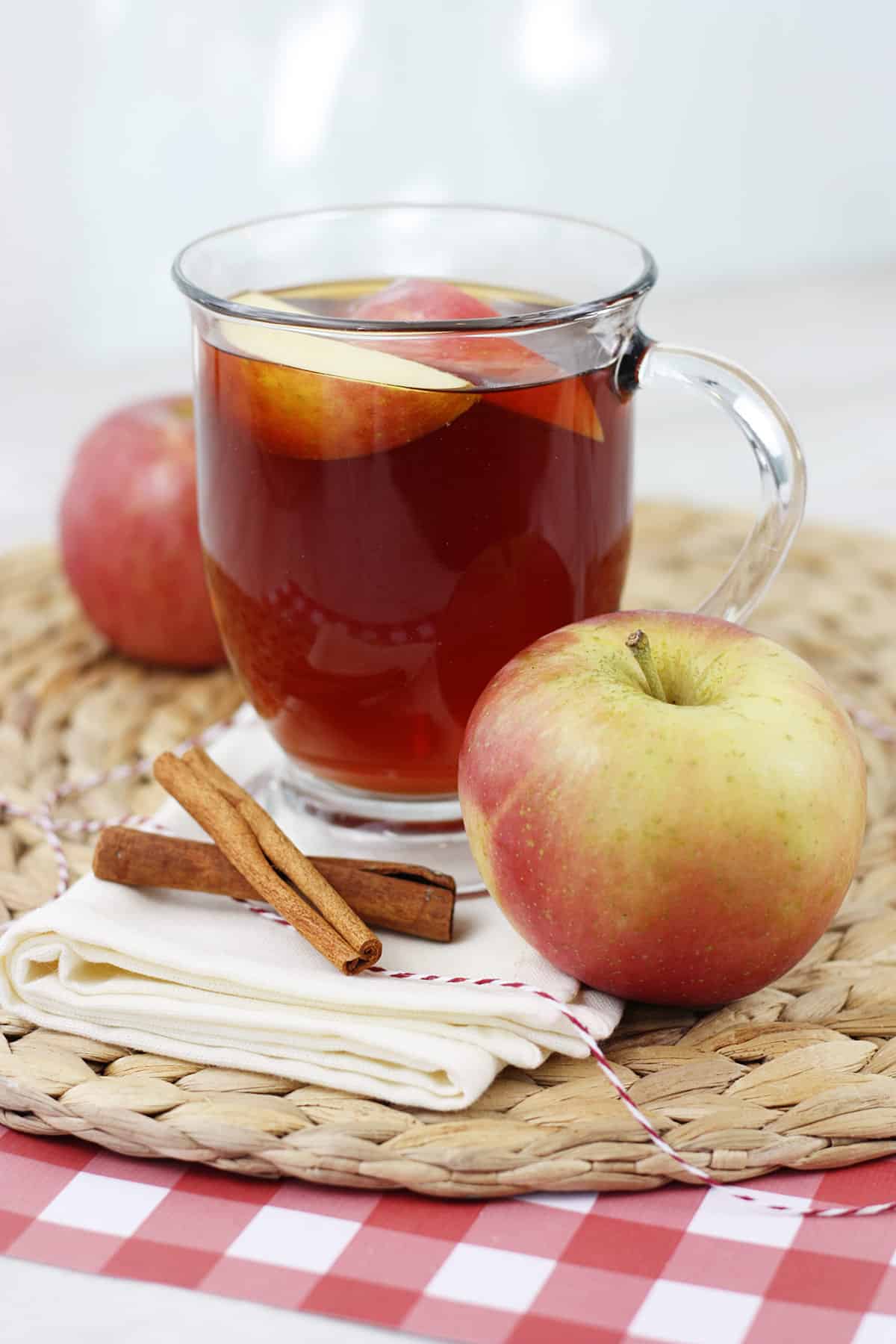A glass mug filled with apple slices and apple tea on a napkin.