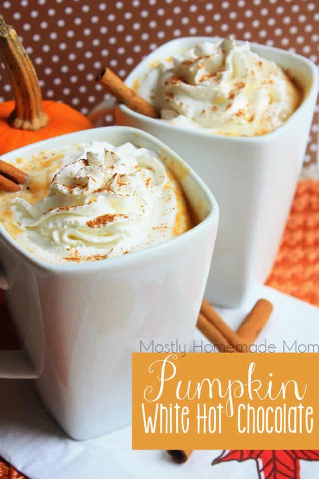 Two white mugs of pumpkin hot chocolate topped with whipped cream and nutmeg