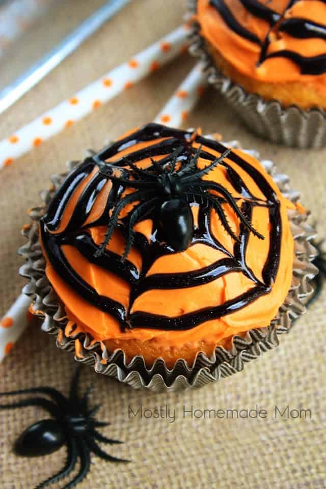 A Halloween spider web cupcake next to orange polka dot straws