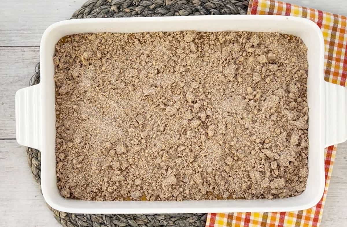 Pumpkin crumb cake in a white baking dish ready to be put into the oven.