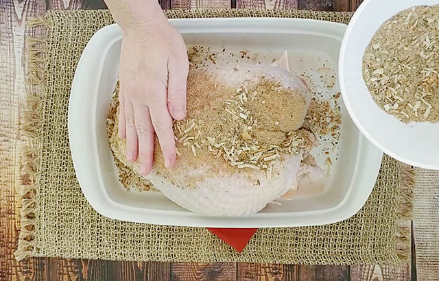 Rubbing seasonings on turkey breast in a baking dish