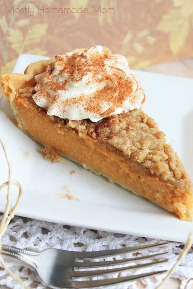 A slice of sweet potato pie on a square white plate with whipped cream