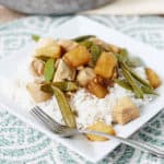 Pineapple chicken with sugar snap peas on a square plate with white rice