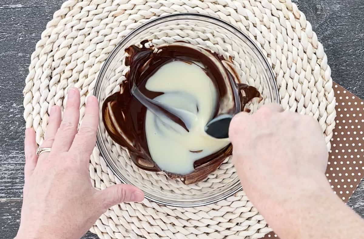 Stirring sweetened condensed milk into melted chocolate.