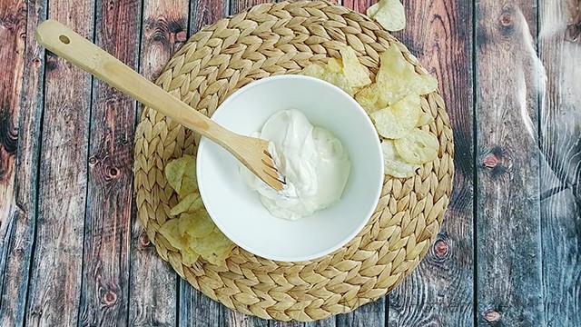 Mixing bowl with sour cream and mayonnaise with a wooden spoon