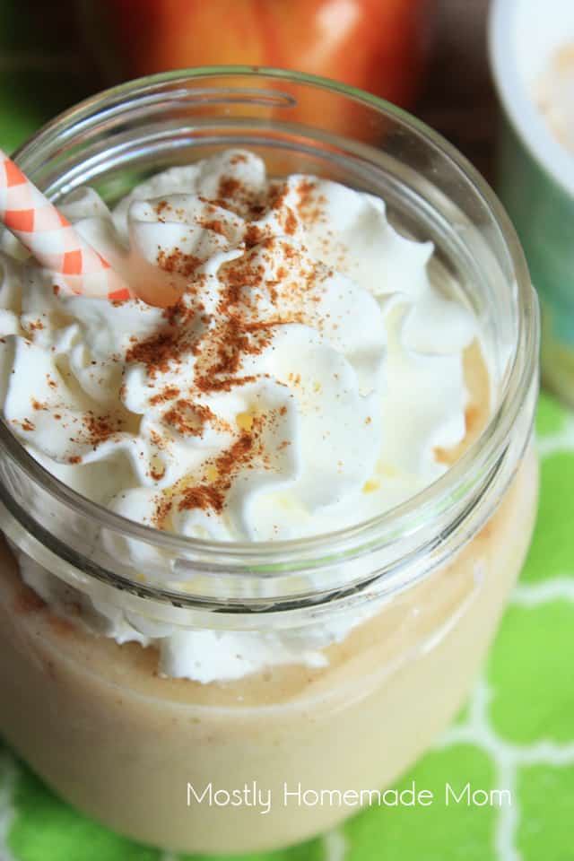 A close up picture of apple cinnamon smoothie with whipped cream and a straw