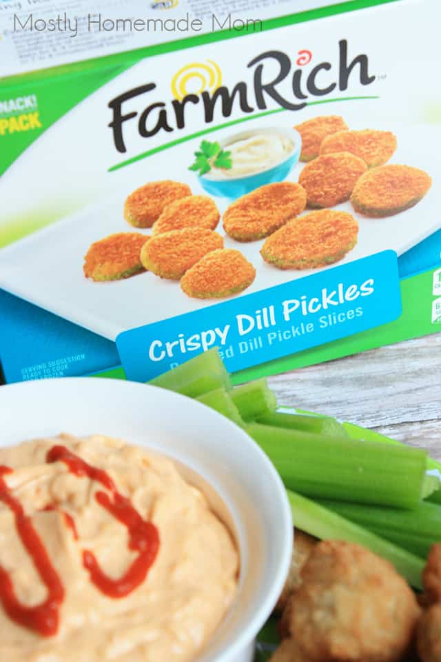 A box of fried pickles next to a bowl of sriracha dip