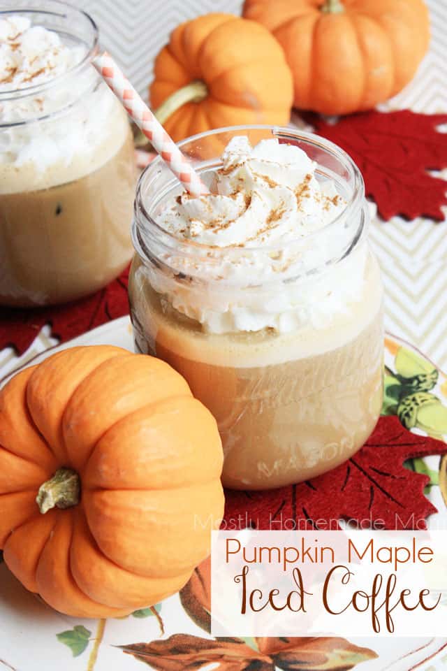 Mason jars filled with pumpkin iced coffee next to small pumpkins