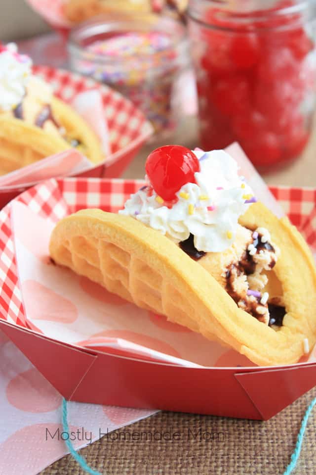 A finished ice cream taco in a paper serving bowl topped with whipped cream and a cherry