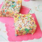 Two fruity pebbles treats on a pink napkin with coconut
