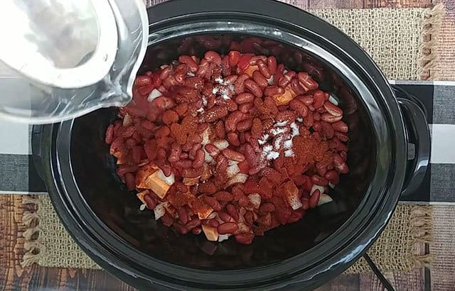Pouring water into a Crockpot to make sweet potato chili