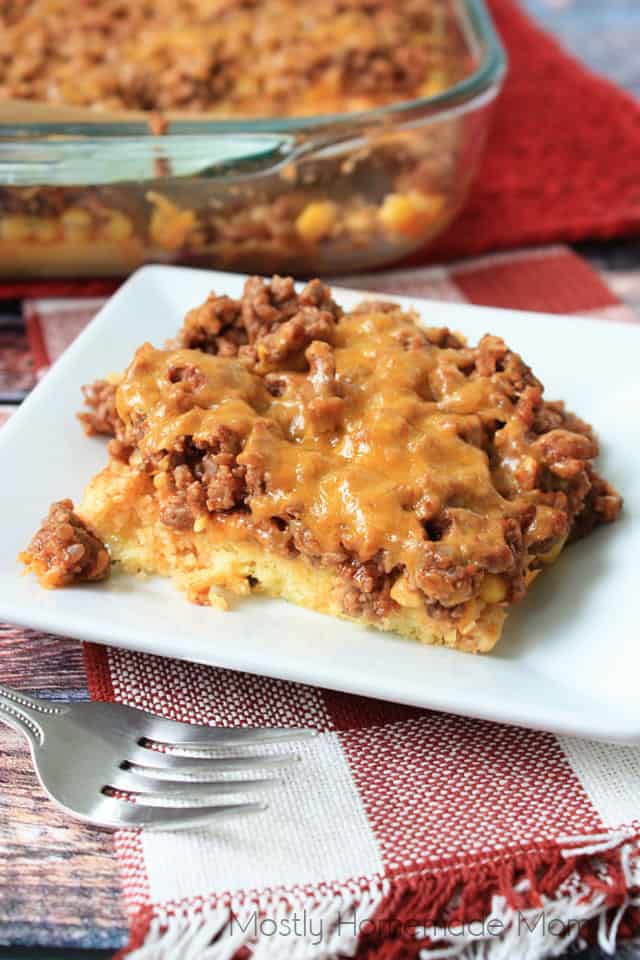 Sloppy Joe Cornbread Casserole on a white plate with the baking dish in the background
