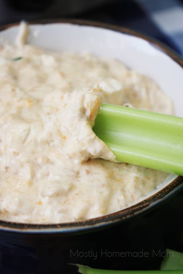 Hot crab dip in a bowl with a celery stick