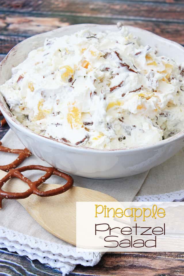 A bowl of pineapple pretzel salad with a wooden mixing spoon next to it