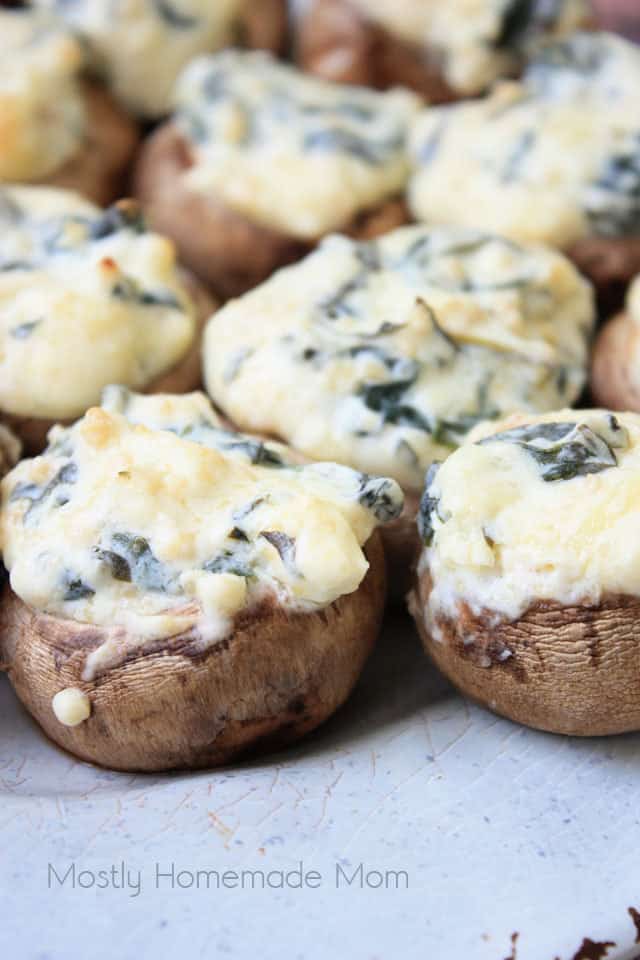 Close up picture of spinach dip stuffed mushrooms on a white plate