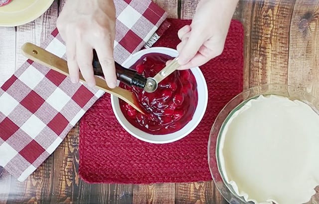 Adding almond extract to cherry pie filling in a mixing bowl