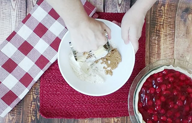 Mixing crumb topping ingredients in a bowl with a pastry blender
