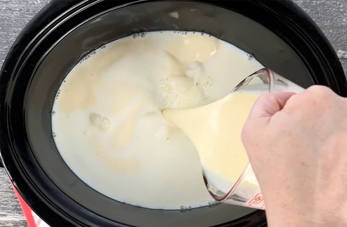 Pouring eggnog into a slow cooker.