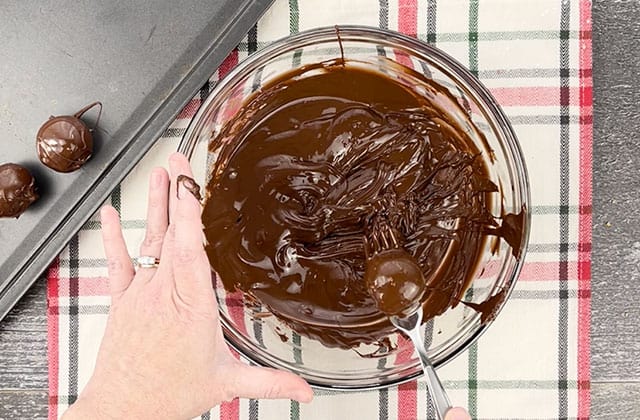 Coating the peanut butter bon bons in melted semi sweet chocolate using a fork